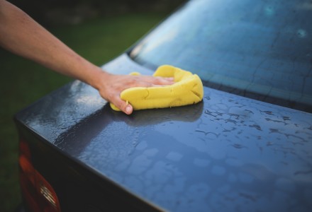 man hand washing black car